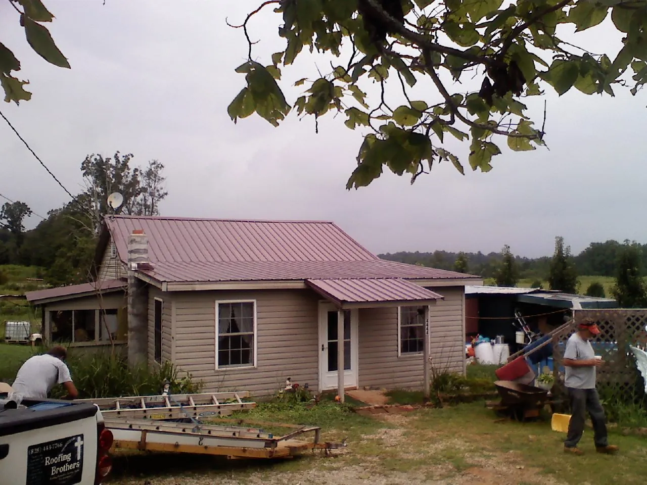 Crew finishing a mauve metal roof on a small farmhouse in Martinsville